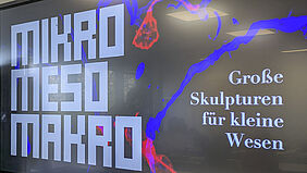 MMM Presentation You can see a screen with a poster hanging next to it.