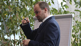Lorenz Präsentation Mathias Lorenz hält einen Stift in der Hand und steht vor einem Flipchart. Er gestikuliert in Richtung Publikum.