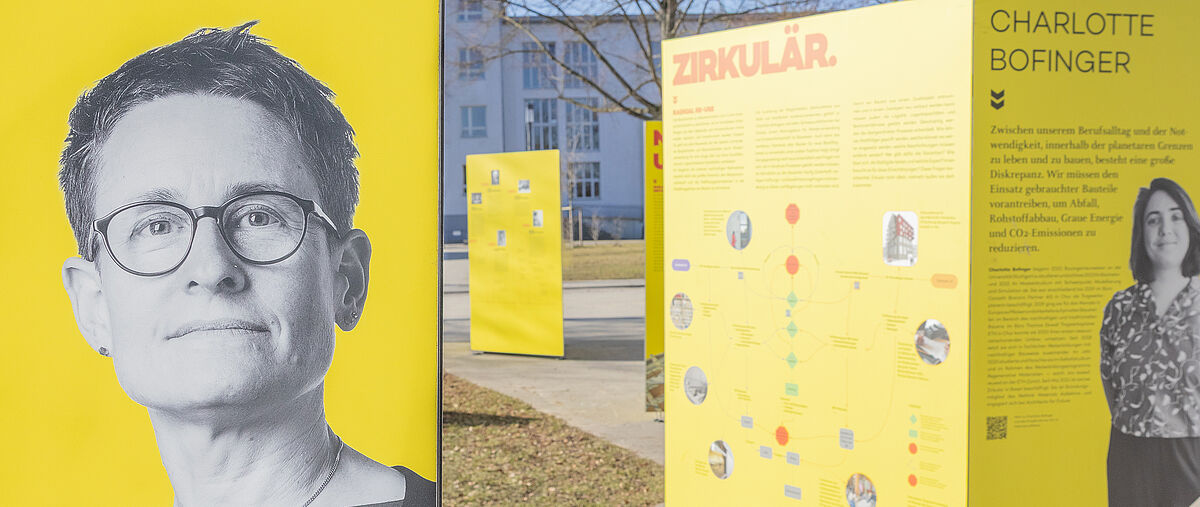 Outdoorausstellung mit großen gelben Flächen im Sonnenschein, darauf mehrere Fotos von Bauingenieurinnen und erklärende Texte