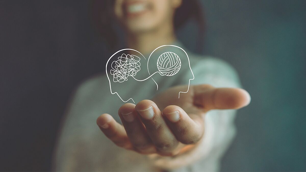 Mental First Aid Grafik: Zwei Köpfe, einander abgewandt, links mit Wirrwarr im Kopf, rechts mit einem geordneten Knäuel im Kopf