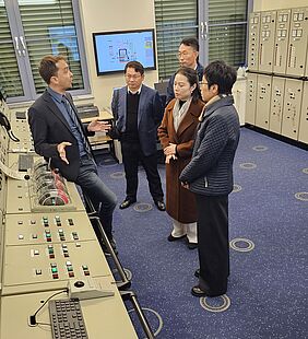 Georg Finger steht am Leitstand links im Bild, während im vier chinesische Personen bei denERläuterungen zusehen.